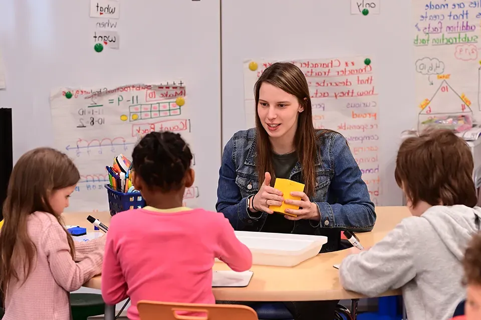 College student teaching three elementary schoolers