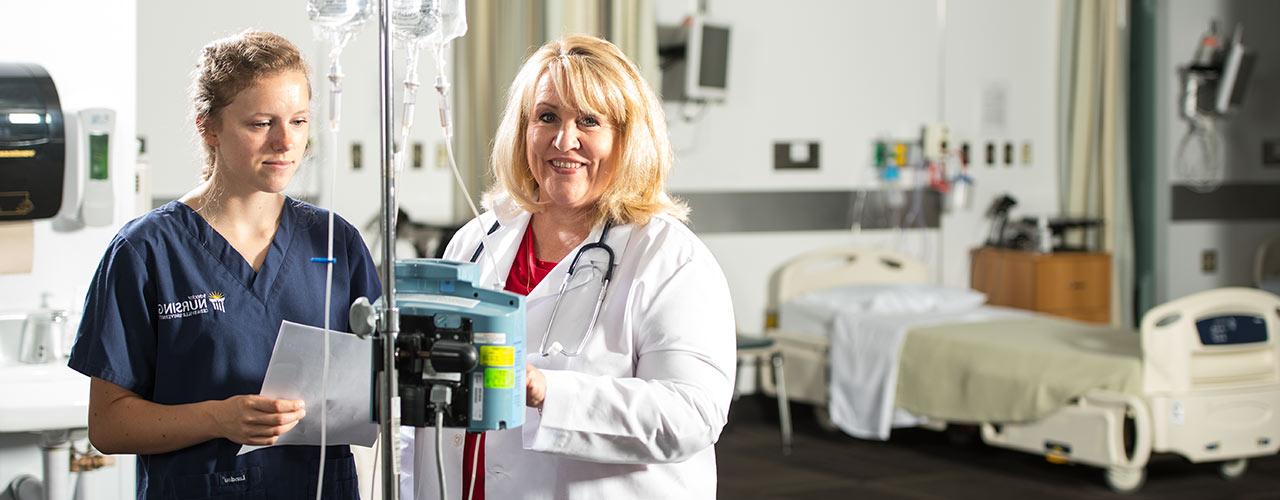 Nurse Educator instructs a female nursing student how to use equipment