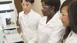 Pharmacy people in white lab coats standing working with equipment