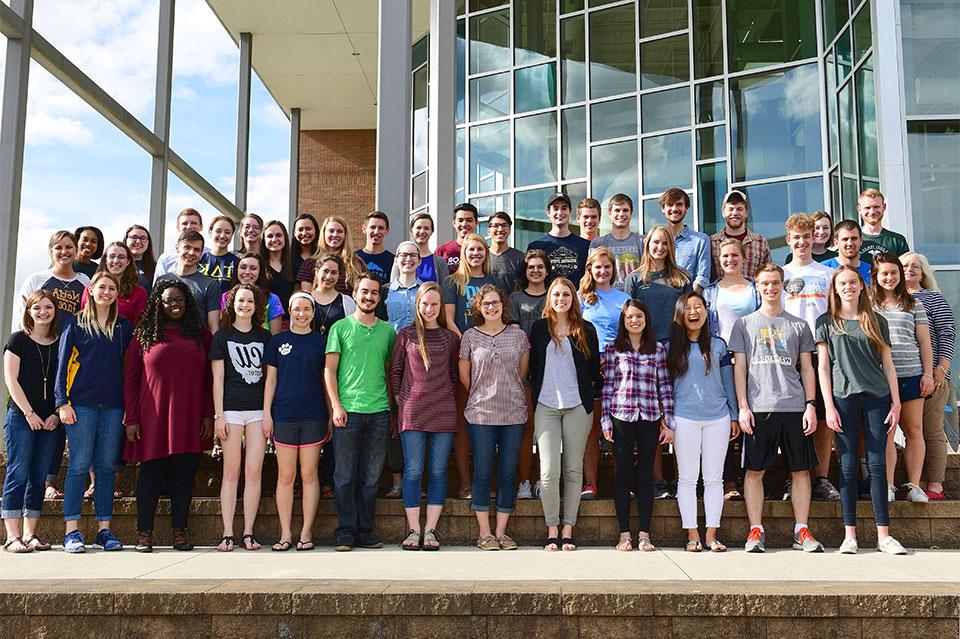 Group picture of dozens of student tutors outside on the BTS Center stairs on sunny day.