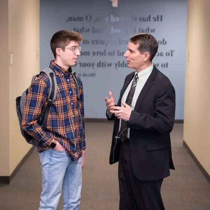 Two men talking in a hallway.